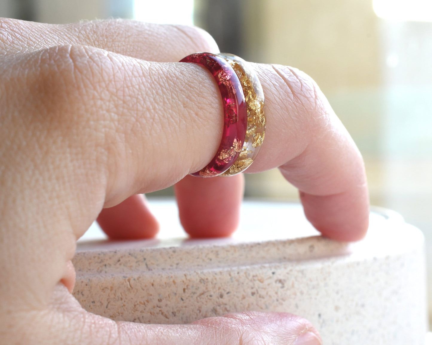Close-up of a hand wearing two rings on a blurred background
