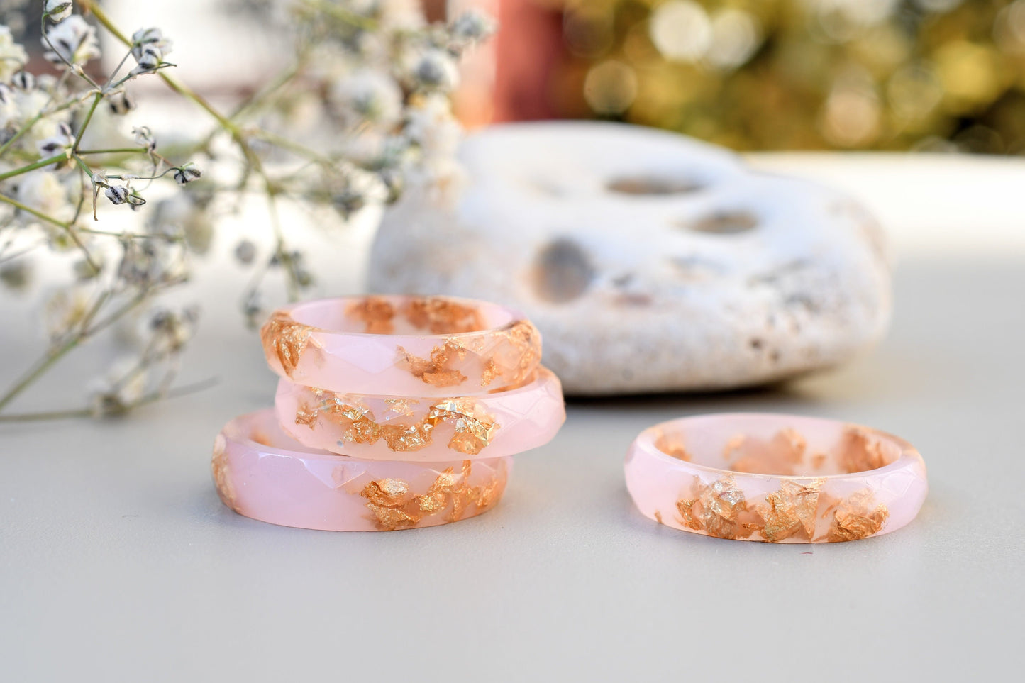 Set of pink rings with gold accents on a light surface with blurred natural background