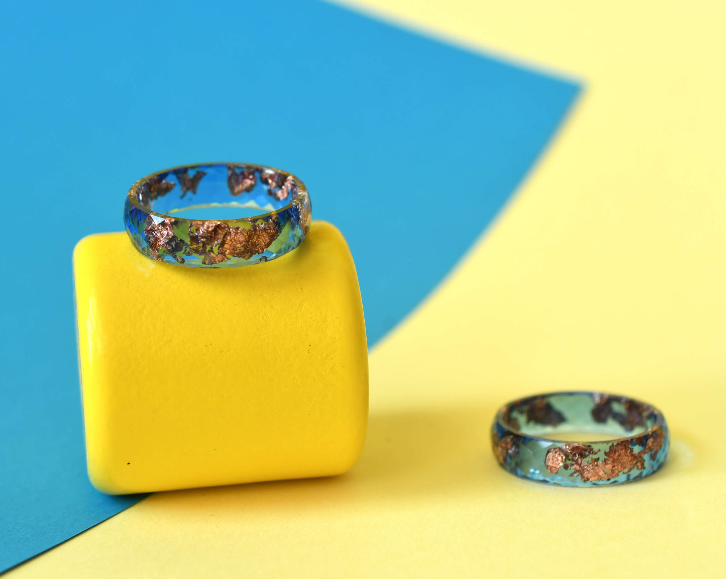 Close-up of metallic rose gold flakes in blue resin ring