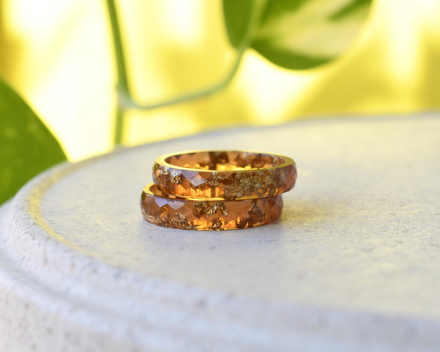 Two amber-colored rings on a white surface with a blurred green background
