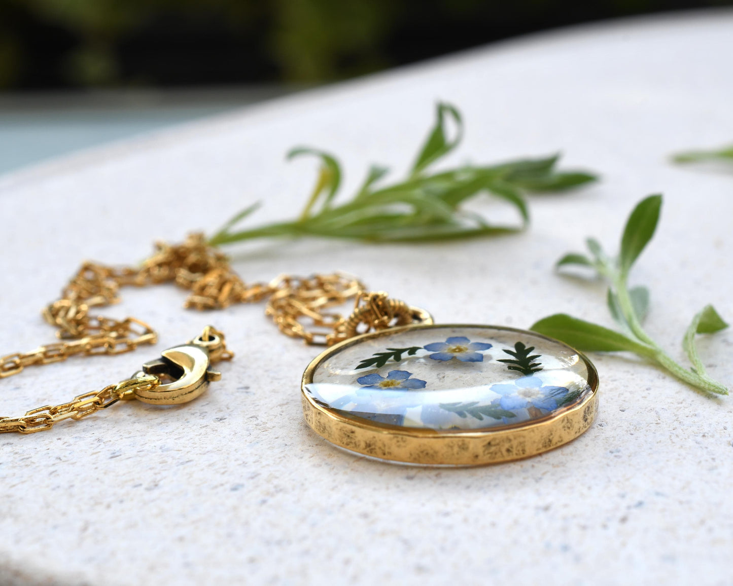 Forget-me-not resin pendant displayed on a tray, highlighting the intricate flower details and crystal-clear resin.