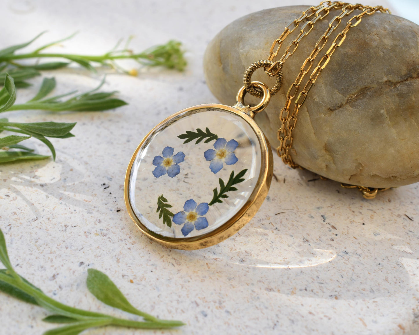 Nature-inspired resin pendant with dried forget-me-not flowers, ready for gift giving, for a sentimental present idea.
