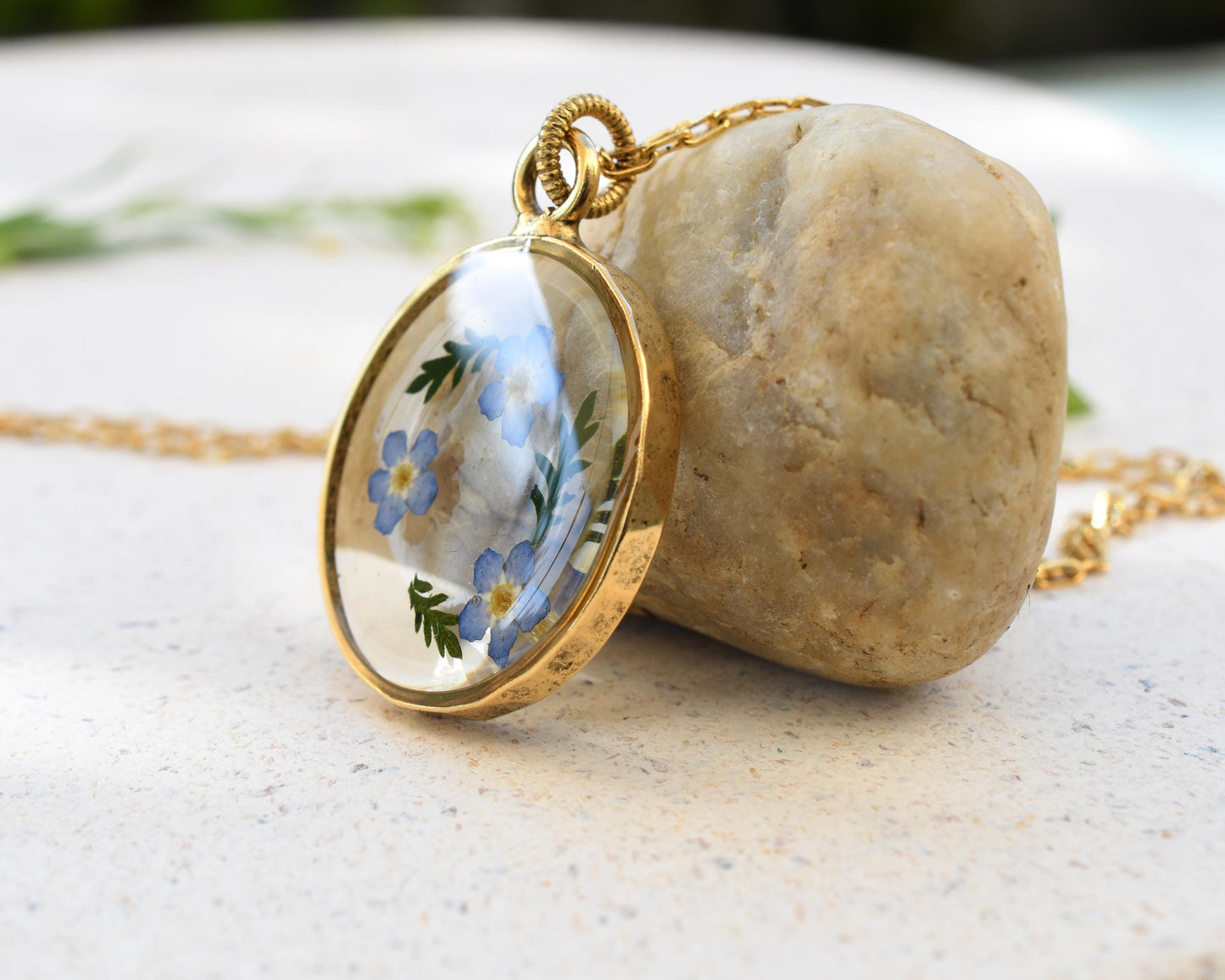 Side view of a forget-me-not resin pendant on a gold chain, emphasizing its lightweight and elegant craftsmanship.