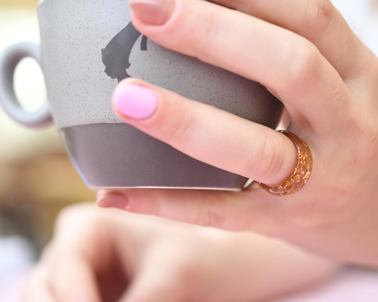 Hand holding a gray mug with a blurred background