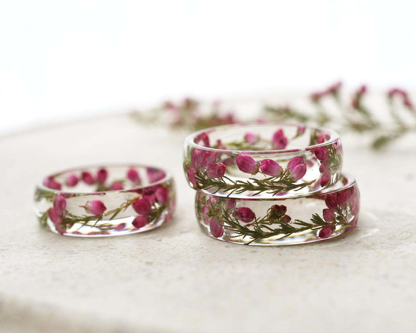 Clear resin rings with pink flowers on a white surface