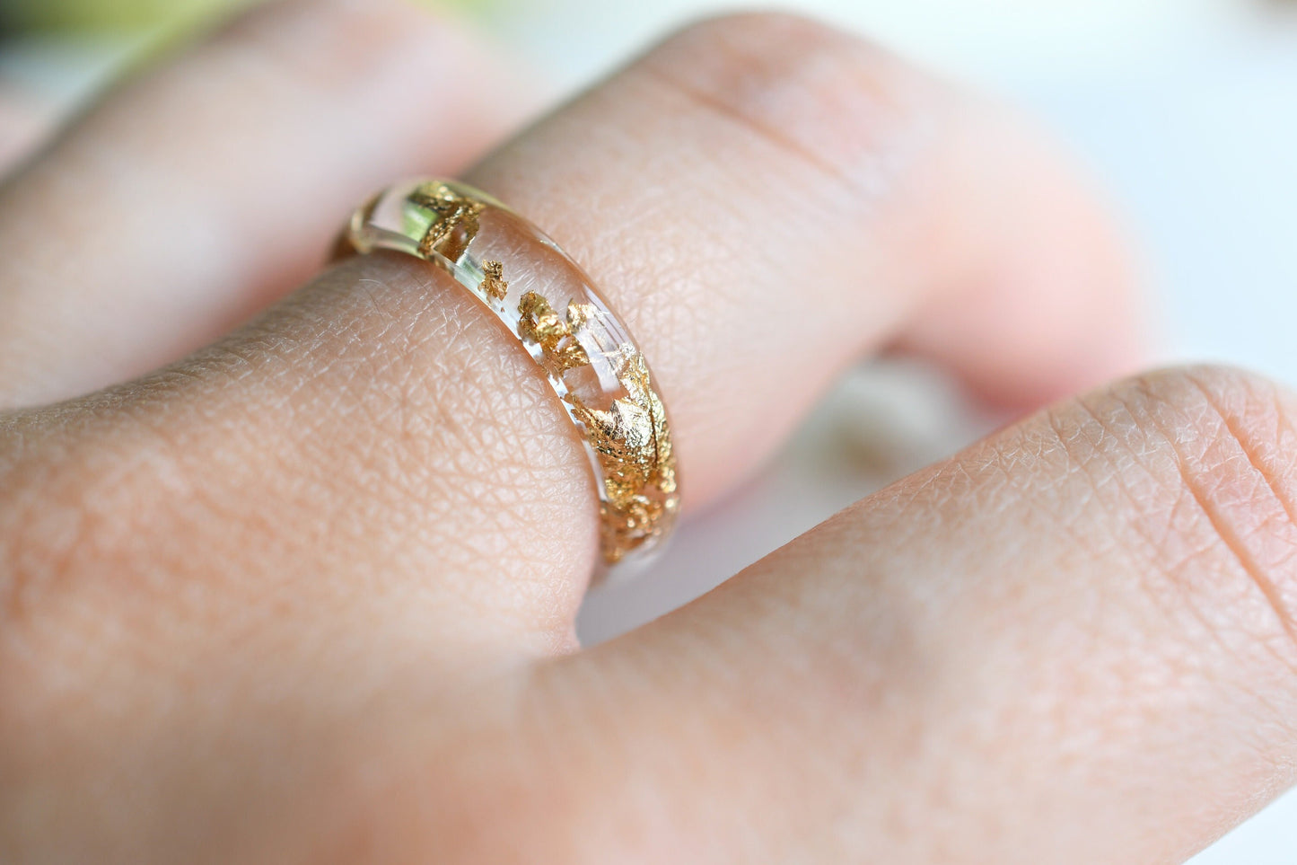 Gold ring on a person's finger with a blurred background