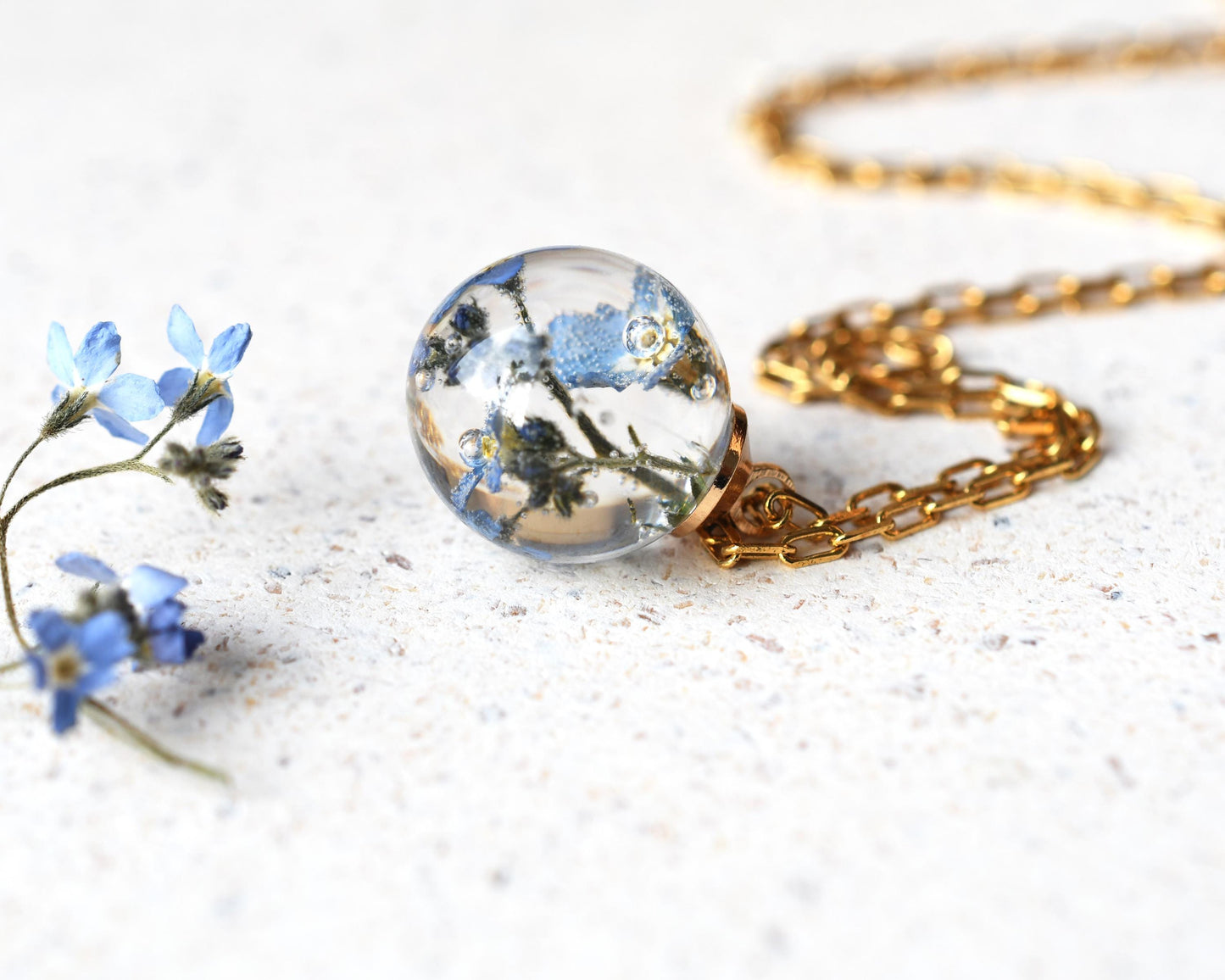 Close-up of gold-plated chain and resin with dried flowers