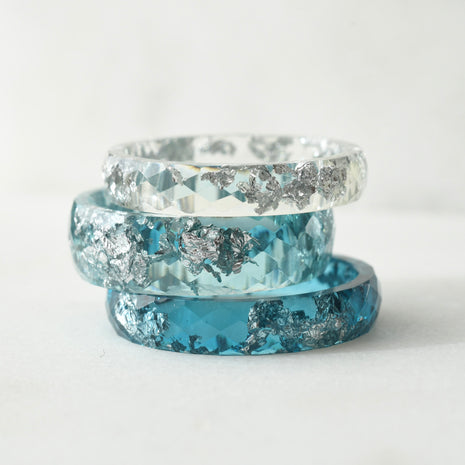 Three blue and silver rings stacked on a white background