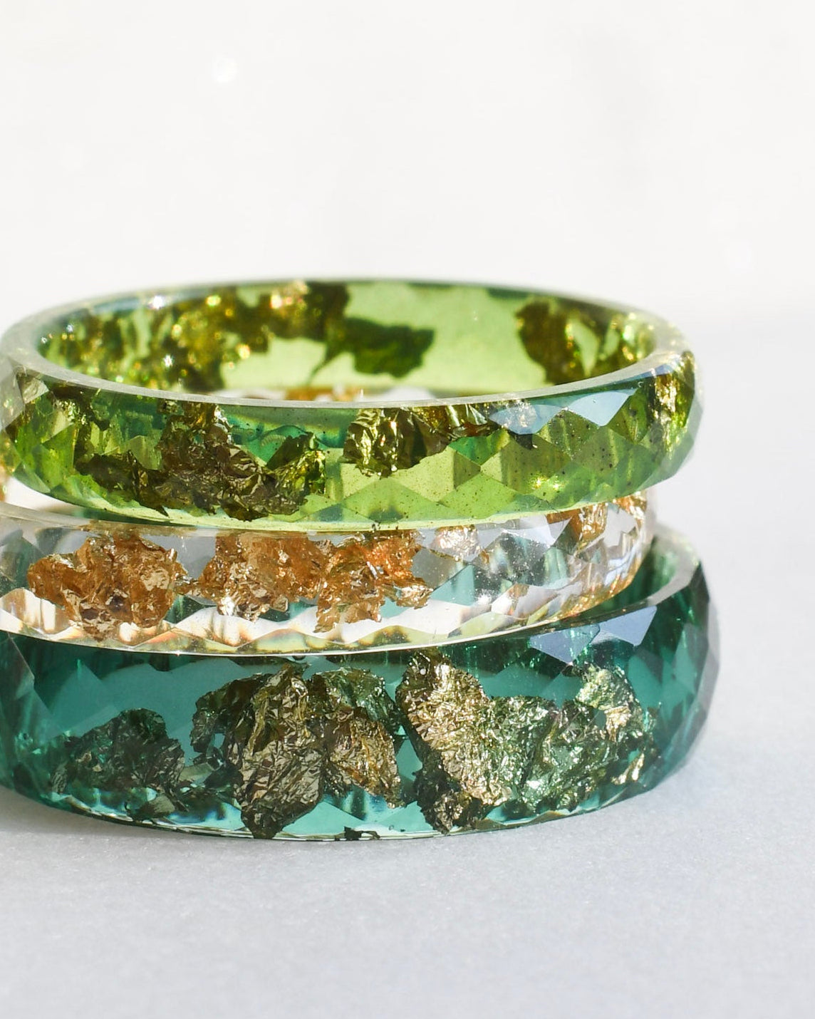 Three green and gold rings stacked on a white background