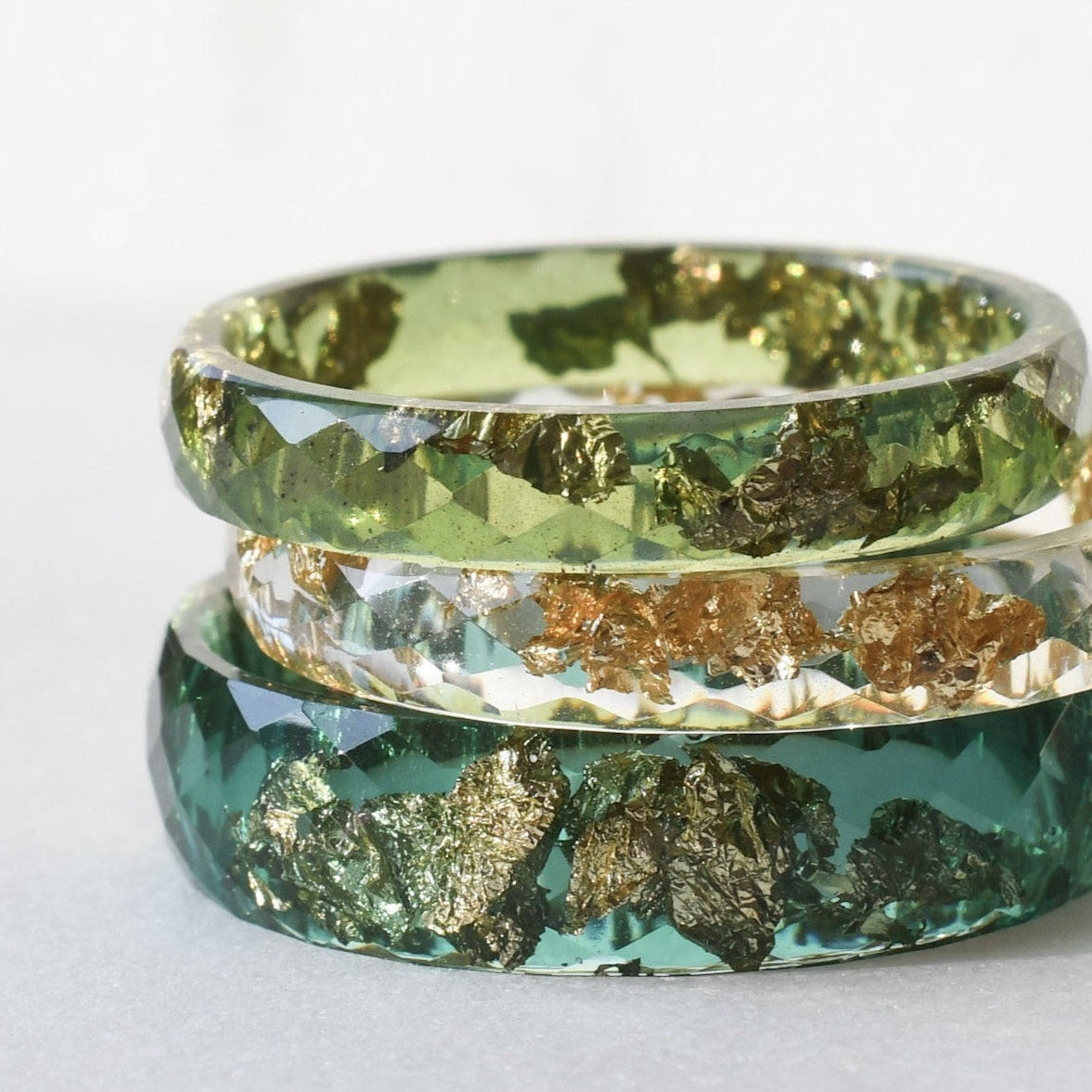 Three green and gold rings stacked on a white surface