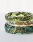 Three green and gold rings stacked on a white surface