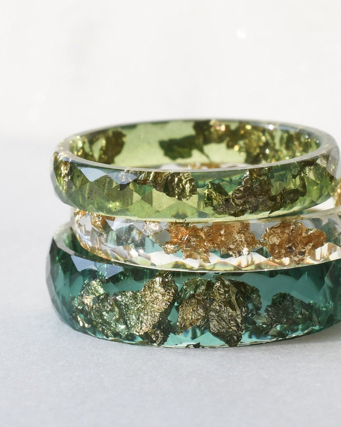 Three green and gold rings stacked on a white surface