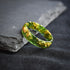 close up alternative men’s wedding ring green gold leaf