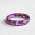 Purple ring with gold flakes on a light gray background