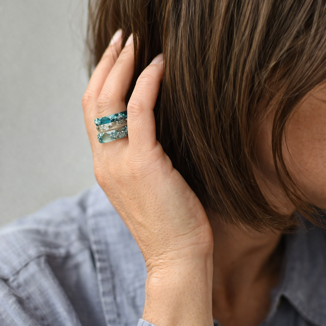Person wearing a ring stack , touching their hair against a neutral background