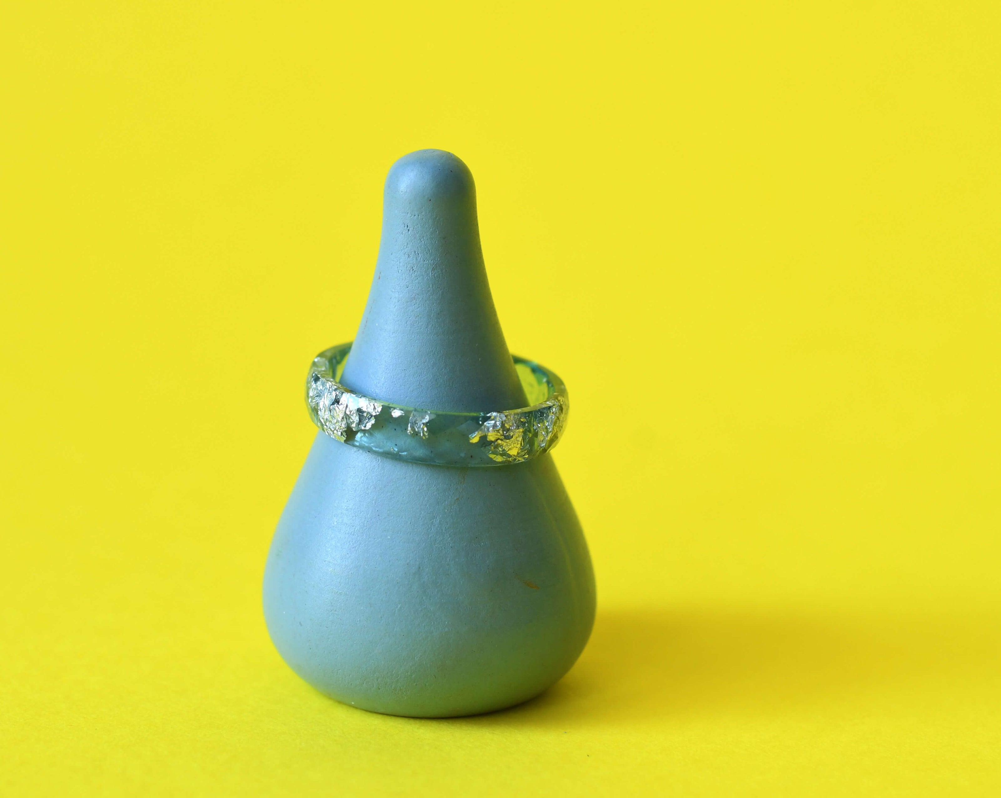 Aqua resin ring with silver leaf on yellow background