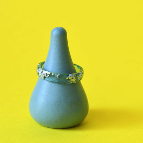 Aqua resin ring with silver leaf on yellow background