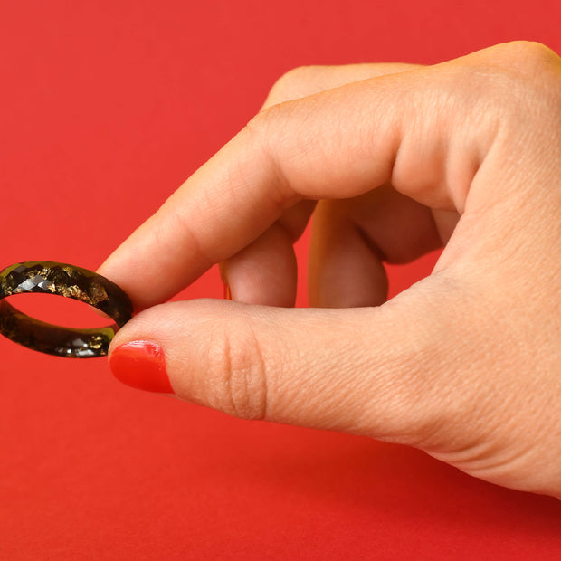 Close-up of faceted black resin ring with gold accents for men