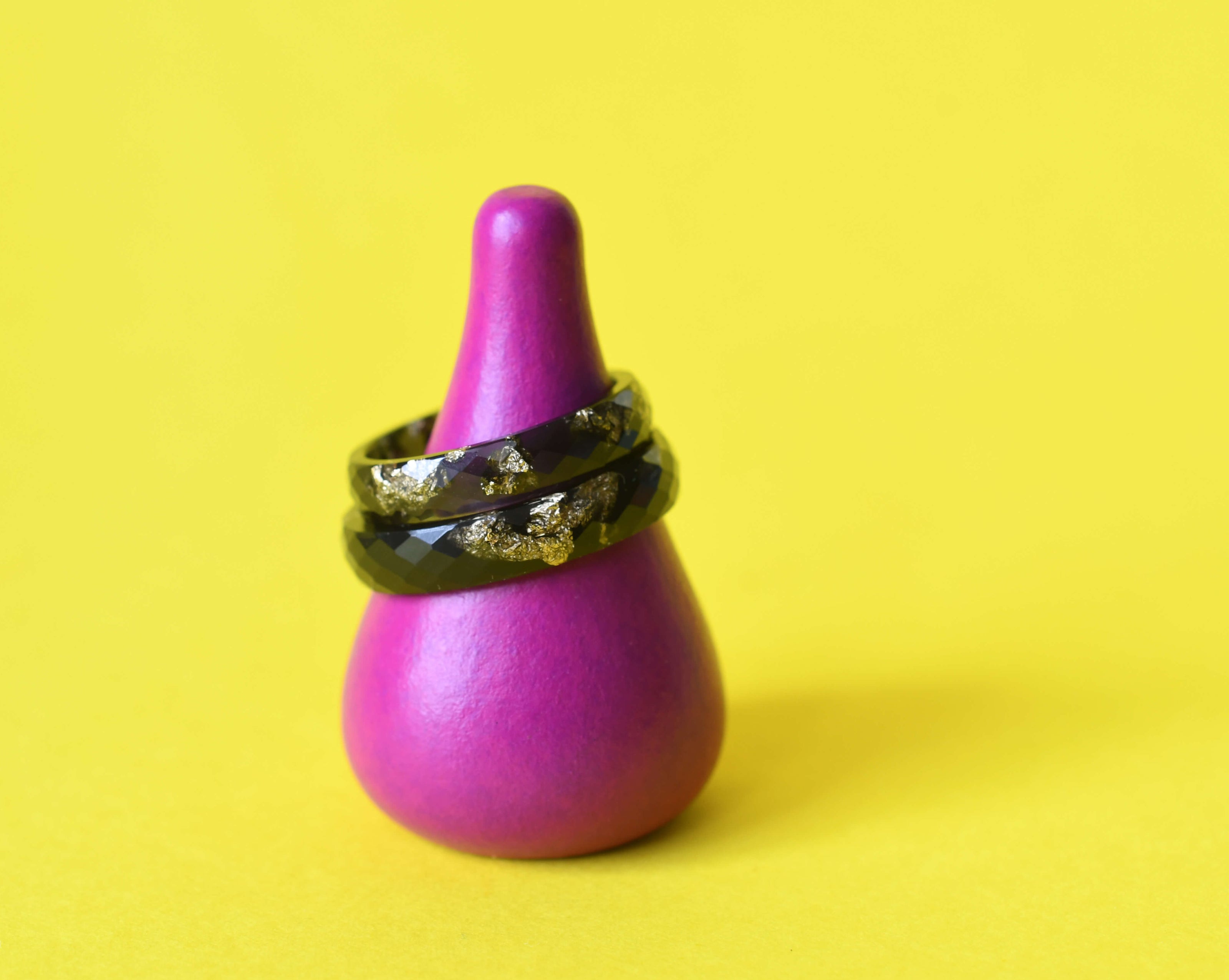 Faceted black resin ring with gold leaf on yellow background