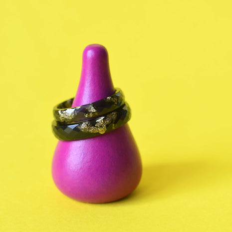 Faceted black resin ring with gold leaf on yellow background