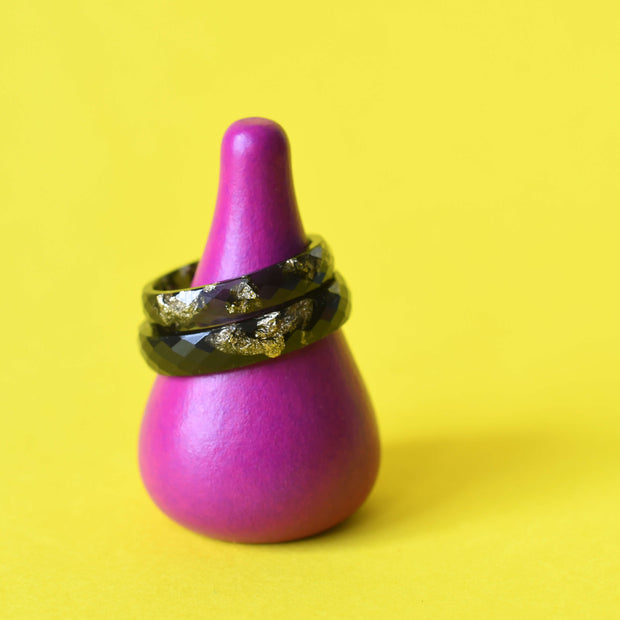 Faceted black resin ring with gold leaf on yellow background