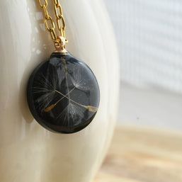 Black resin pendant with real dandelion seed on gold chain, handmade symbolic necklace