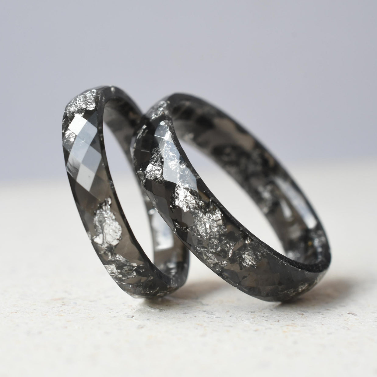 Close-up of glossy black resin with silver flakes — smooth band rings
