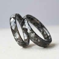 Close-up of glossy black resin with silver flakes — smooth band rings