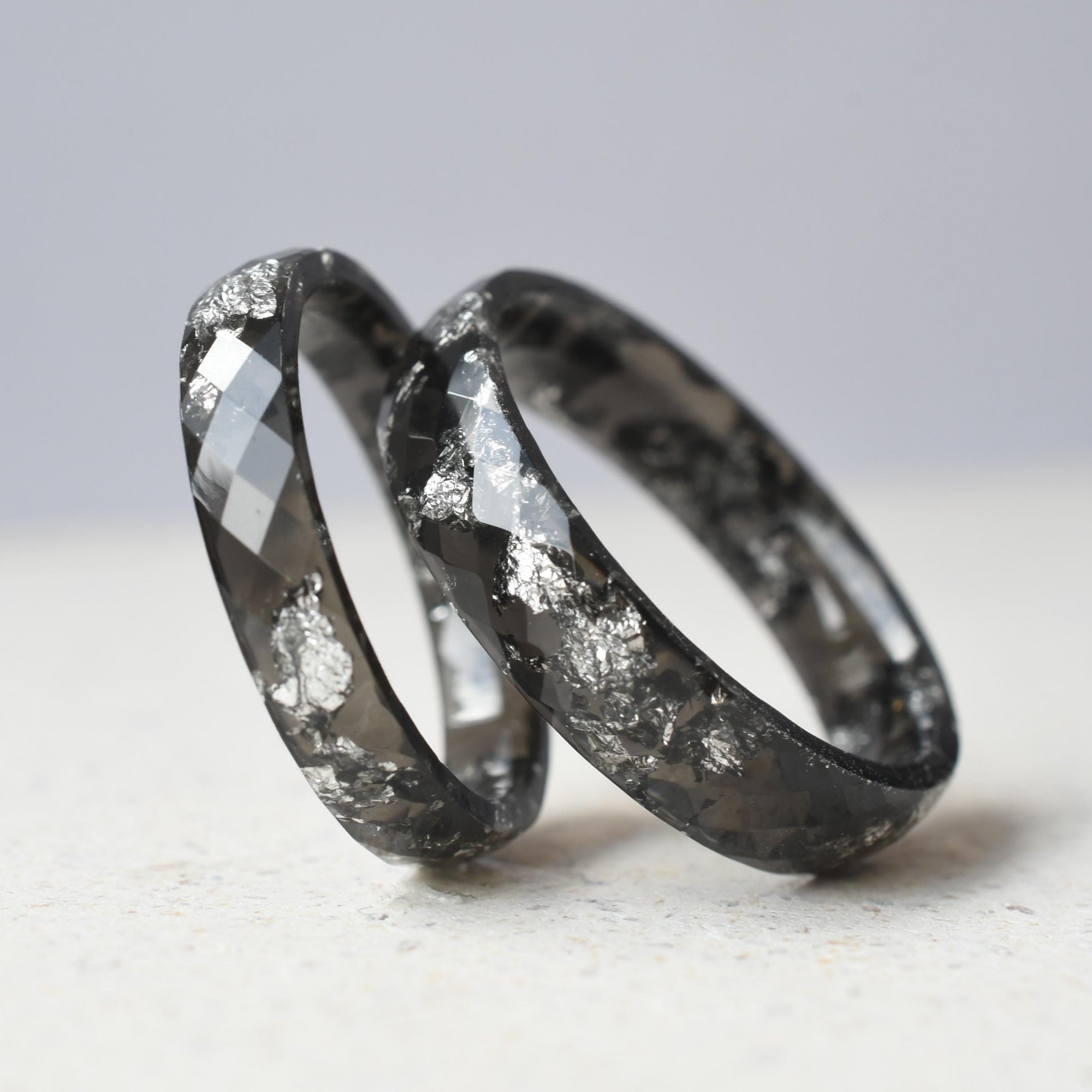Close-up of glossy black resin with silver flakes — smooth band rings