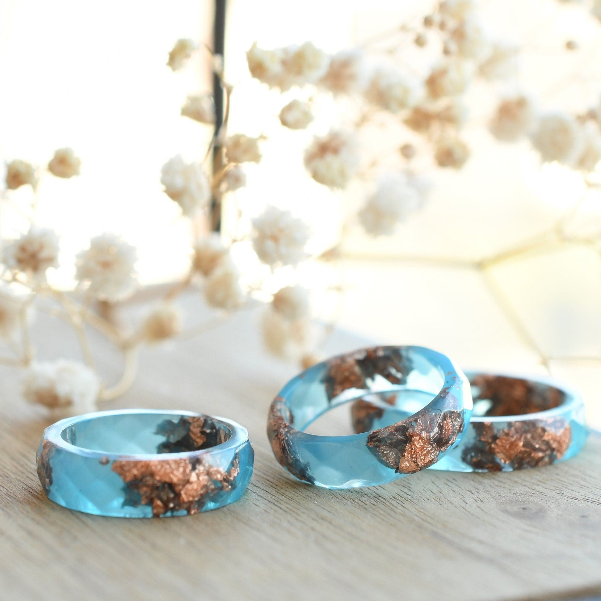 Close-up of blue resin ring with metallic rose gold accents and modern matte finish
