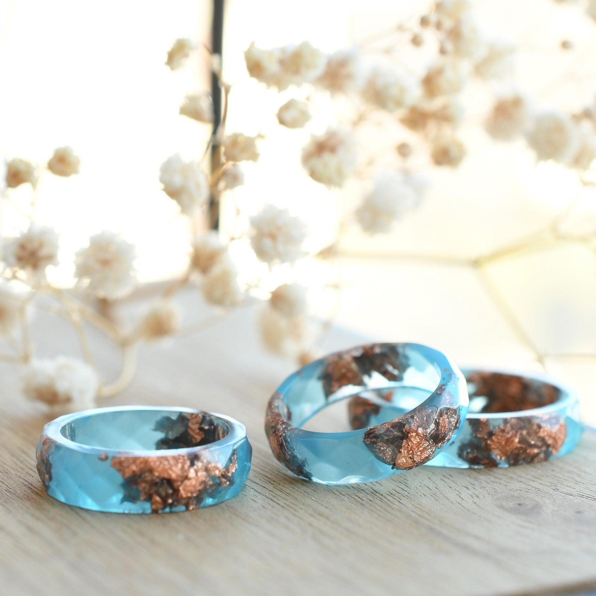 Close-up of blue resin ring with metallic rose gold accents and modern matte finish