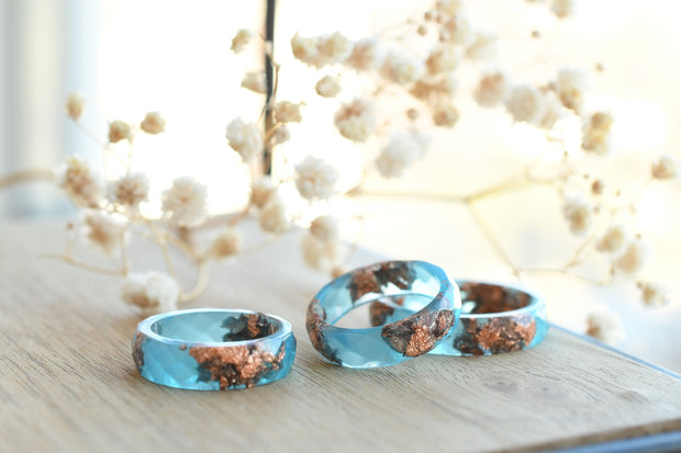 Close-up of blue resin ring with metallic rose gold accents and modern matte finish