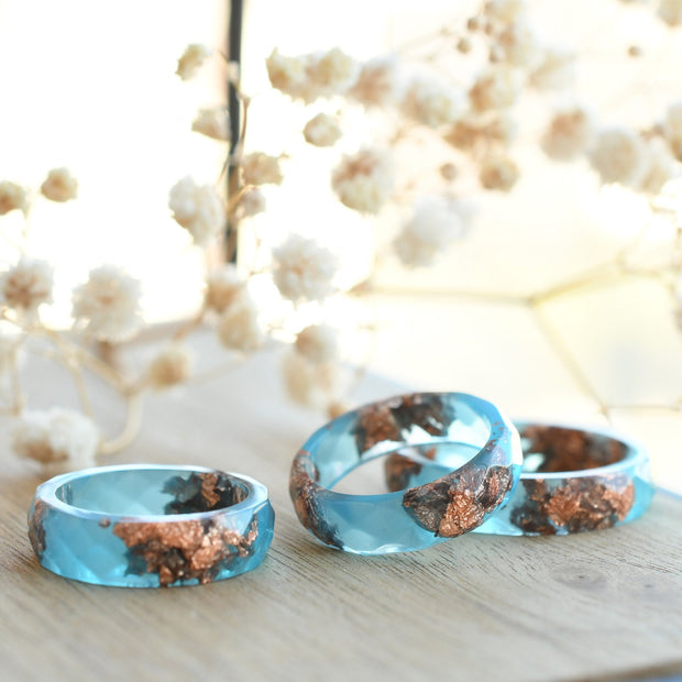 Close-up of blue resin ring with metallic rose gold accents and modern matte finish