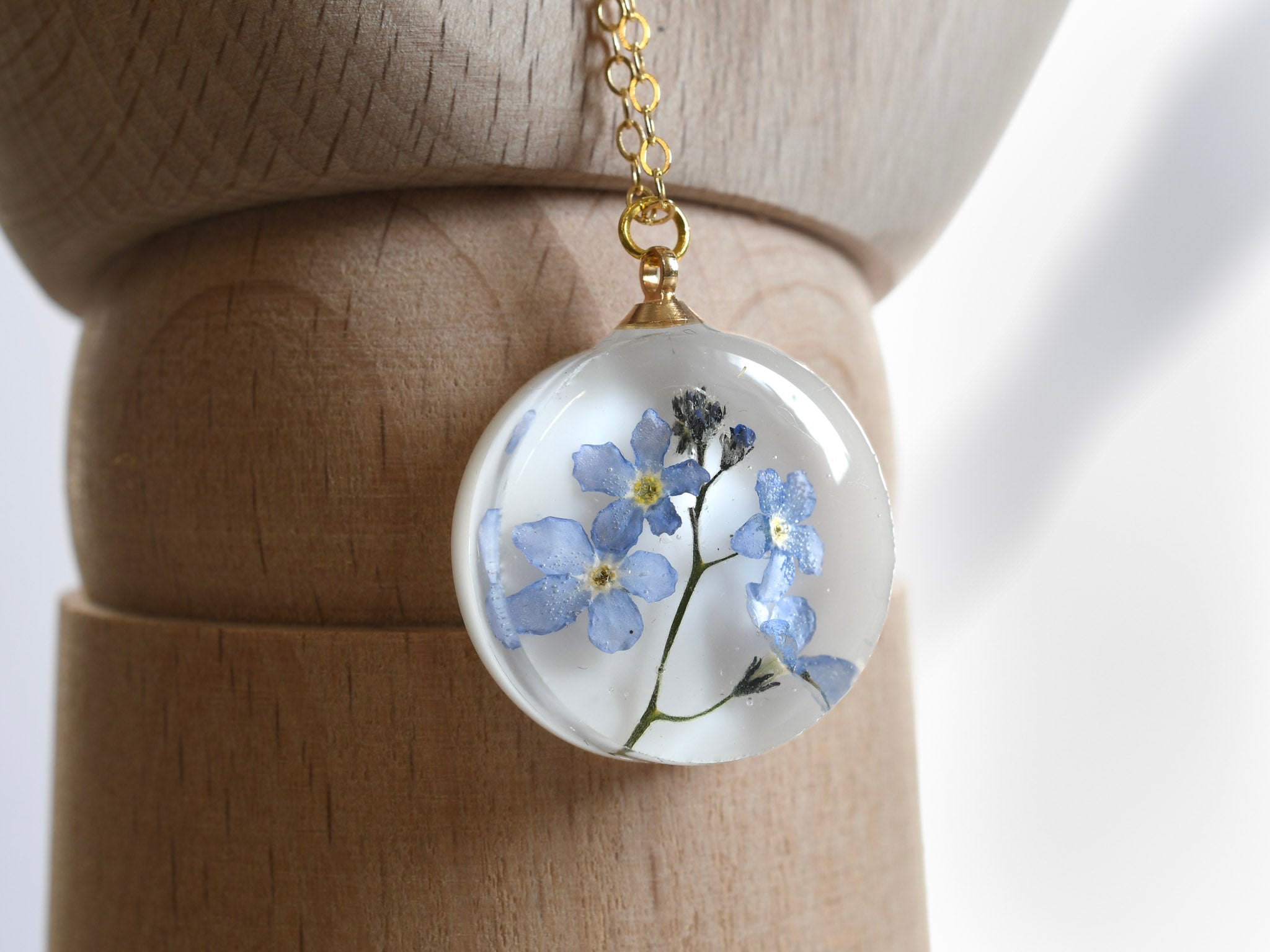 Real blue flower round resin necklace on white background — botanical jewelry