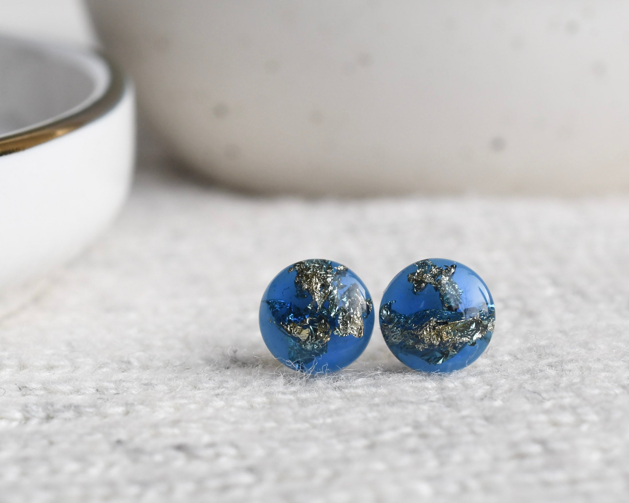 Close-up of blue resin stud earrings with real gold leaf flakes