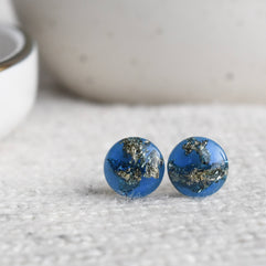 Close-up of blue resin stud earrings with real gold leaf flakes