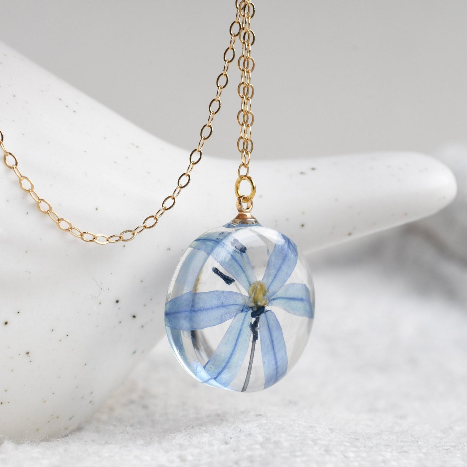 Botanical necklace featuring a vivid blue squill flower in a resin pendant