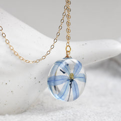 Botanical necklace featuring a vivid blue squill flower in a resin pendant