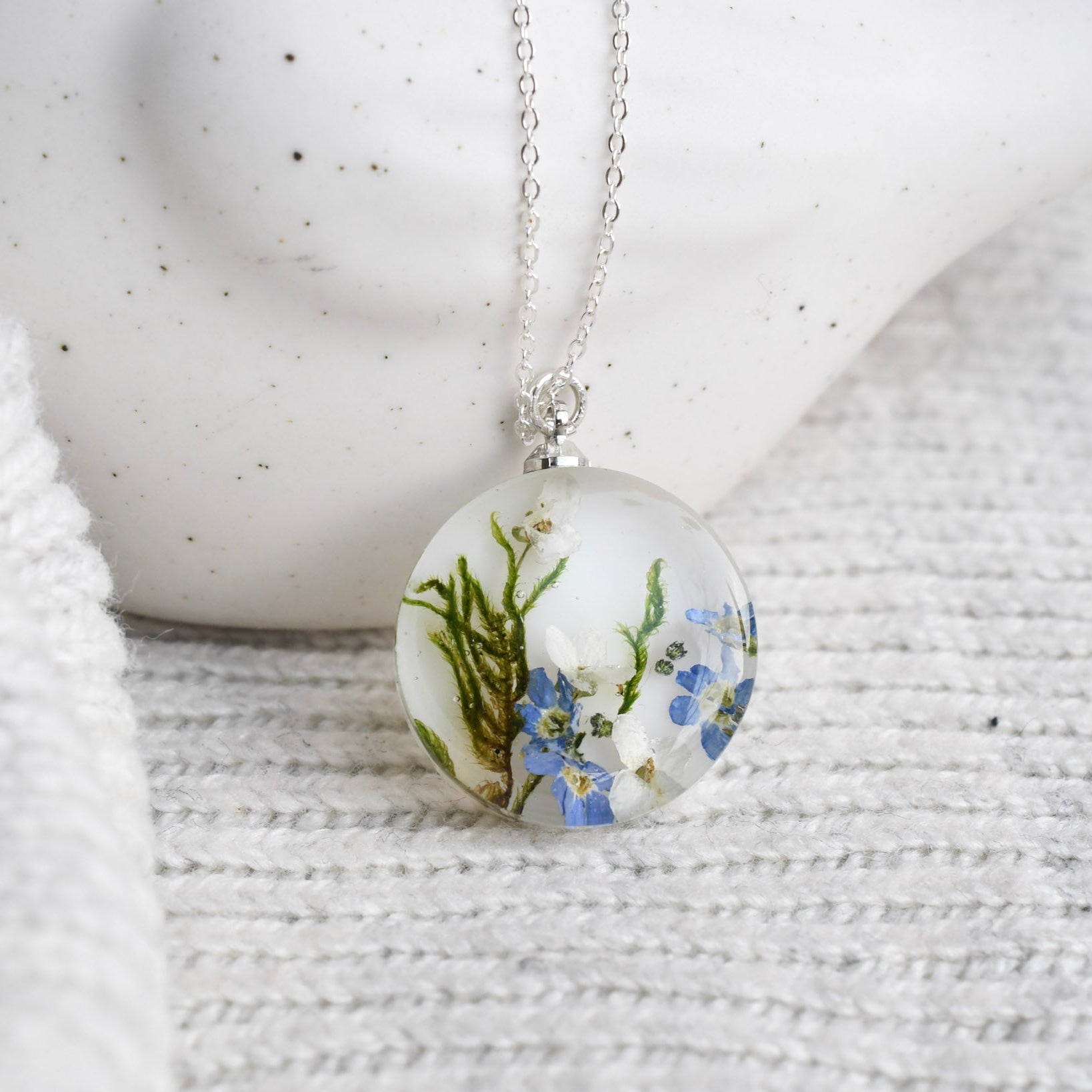 Necklace with a round pendant featuring floral design on a textured white surface