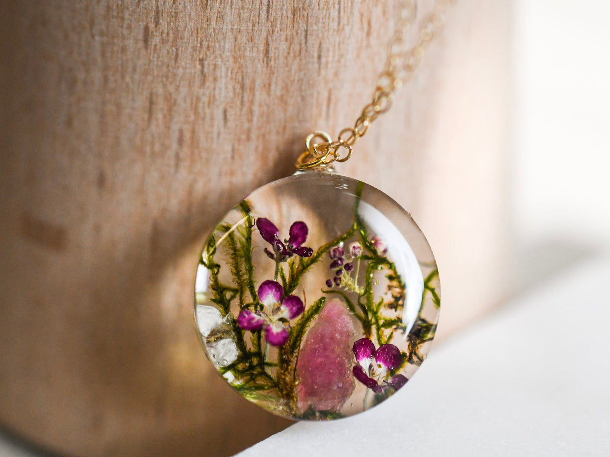 Real moss, pink flower, and tourmaline crystal encased in resin pendant