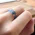 Close-up of a hand wearing a ring with blue floral design on a blurred background