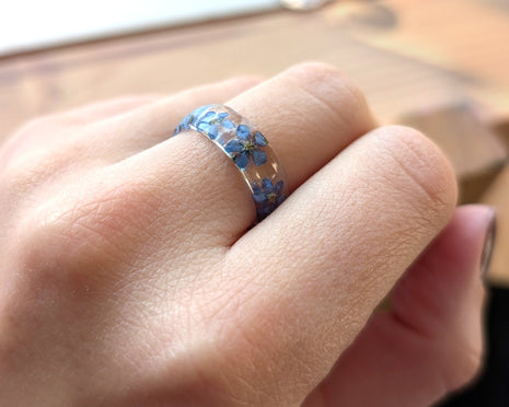 Close-up of a hand wearing a ring with blue floral design on a blurred background