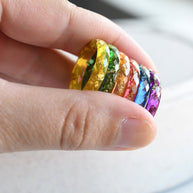 Hand holding a stack of colorful resin rings with a blurred background