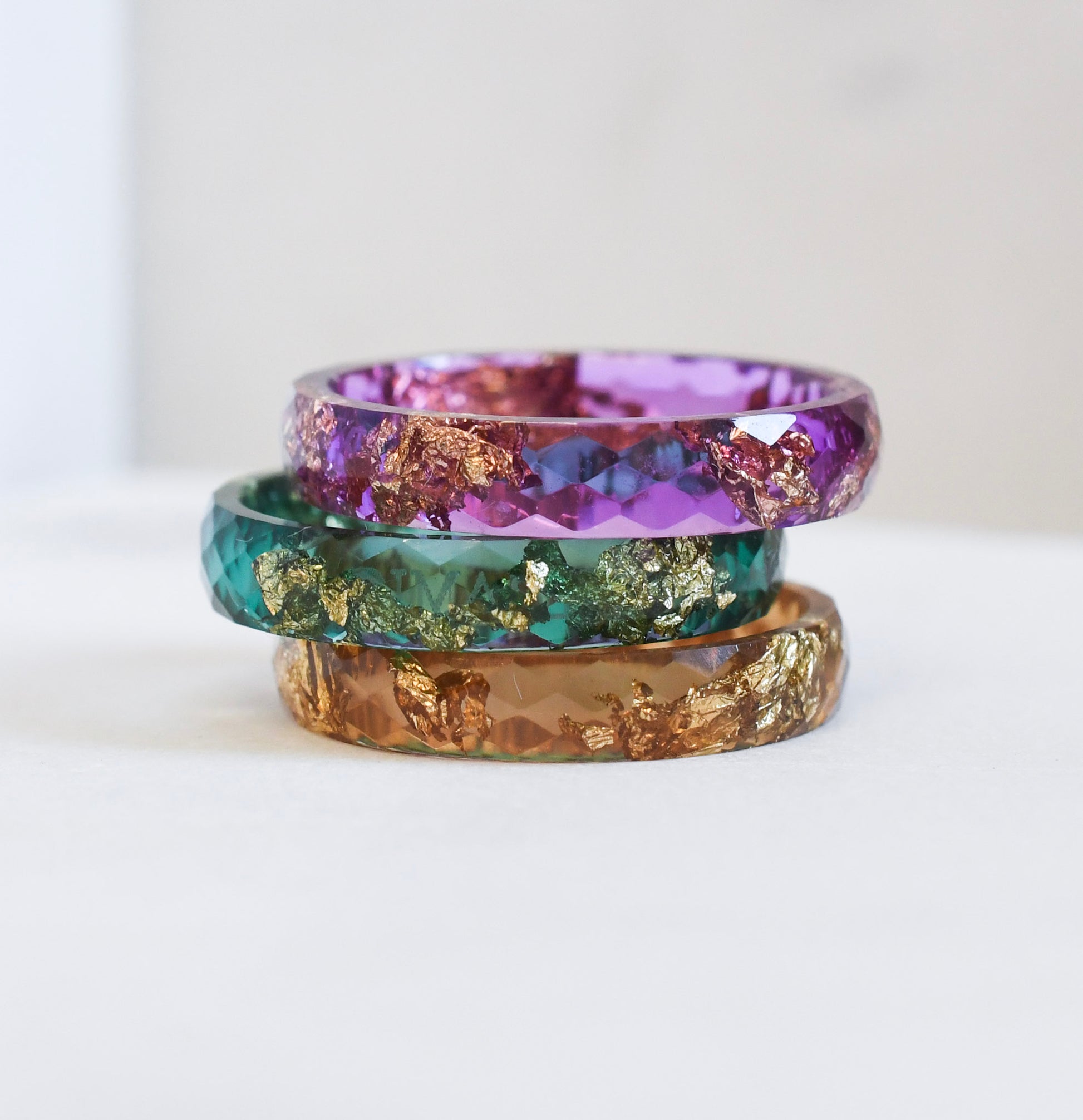 Colorful resin stacking rings set with gold flakes worn together on hand