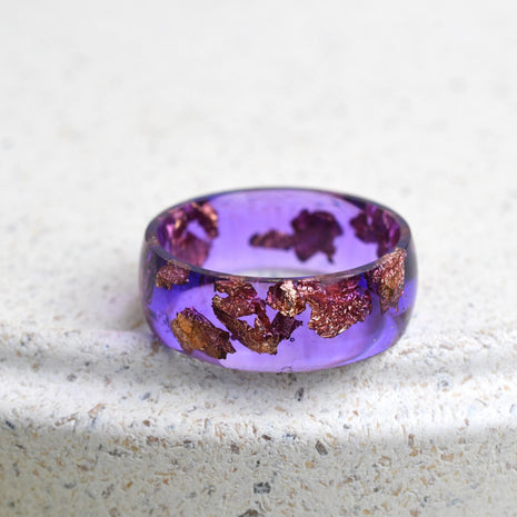 Macro shot of an 8 mm smooth resin ring in cosmic violet with shimmering rose‑gold leaf flakes