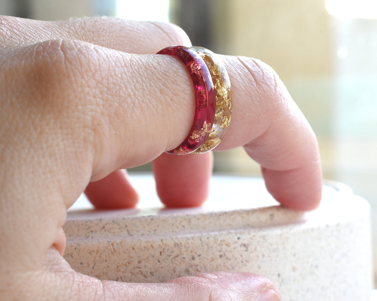 Close-up of a hand wearing two rings on a blurred background