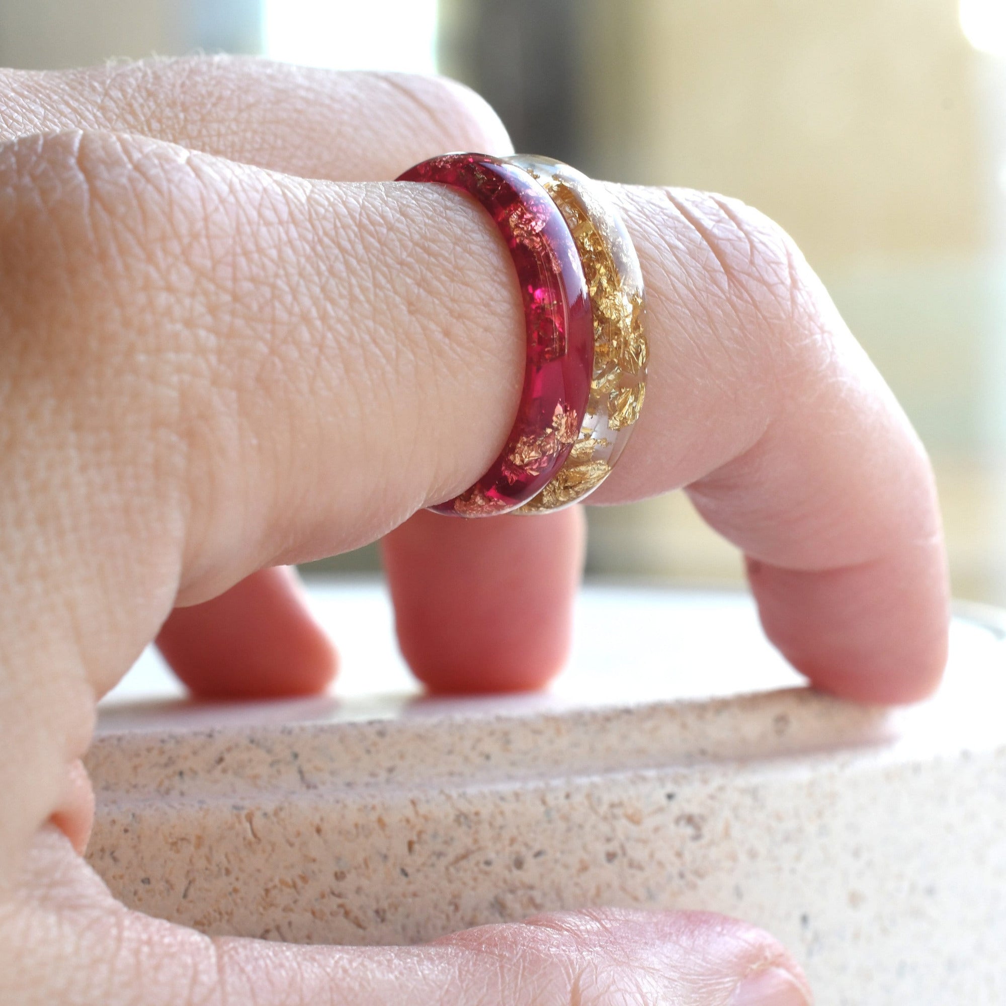 Close-up of a hand wearing two rings on a blurred background
