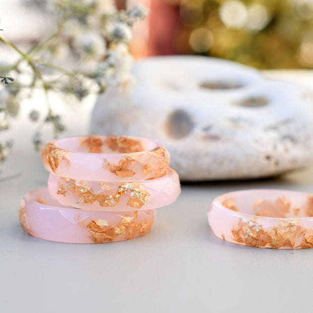 Set of pink rings with gold accents on a light surface with blurred natural background