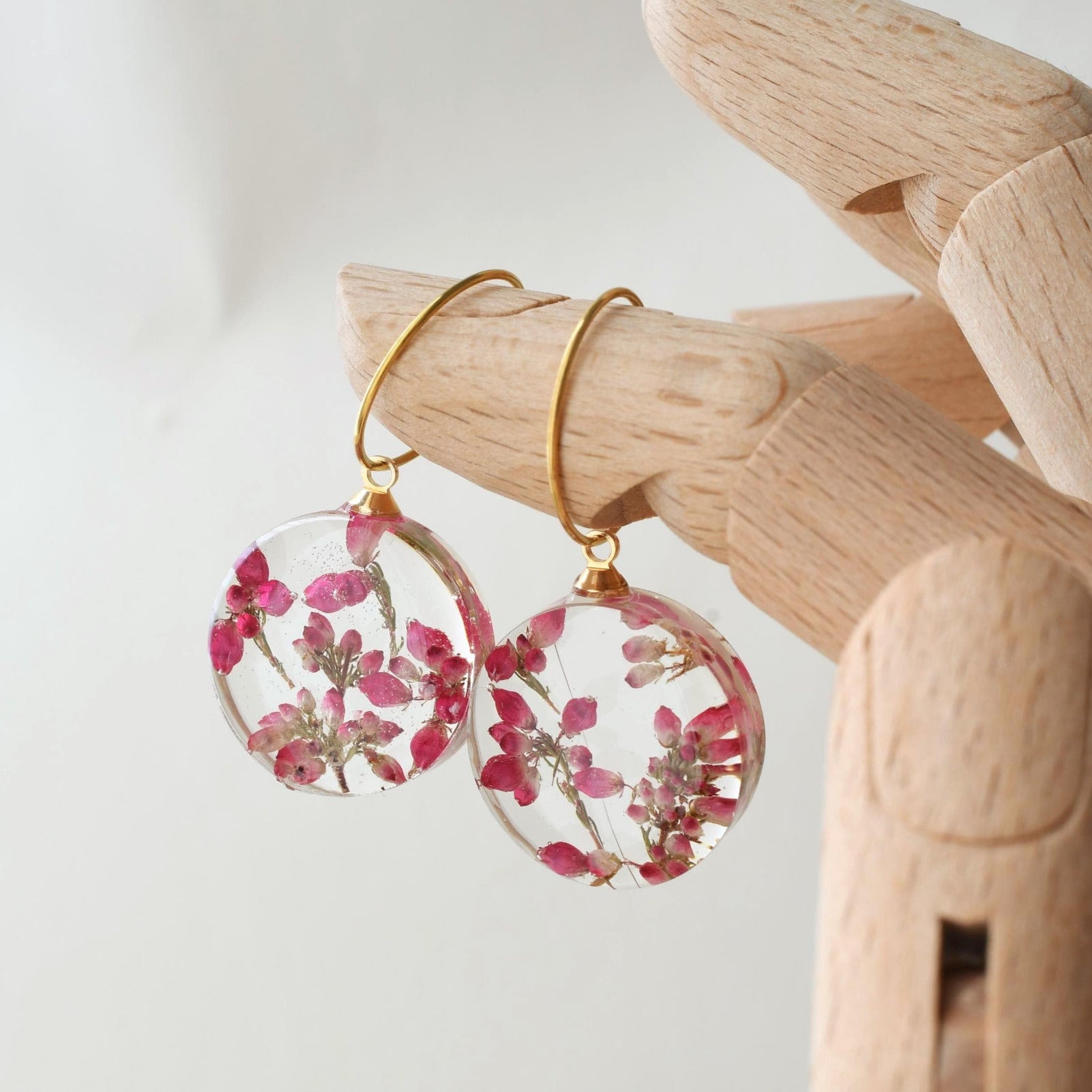 Handmade resin earrings featuring dried heather flowers on gold hoops