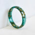 green resin ring with gold flakes on white background